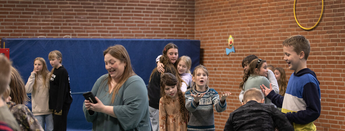 Kinder im Alter von acht bis elf stehen in einer Turnhalle jeweils zu zweit auf den Zeitungen. Noch gibt es eine große Fläche, auf der sie stehen können. Pro Runde wird die Zeitung nämlich immer kleiner.