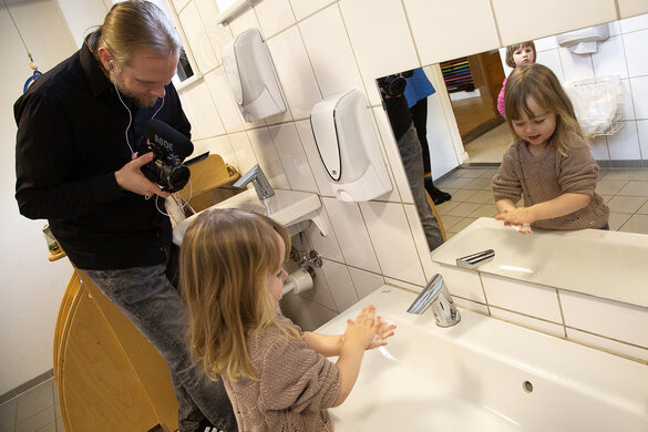 Ein Kind wird beim Händewaschen gefilmt.