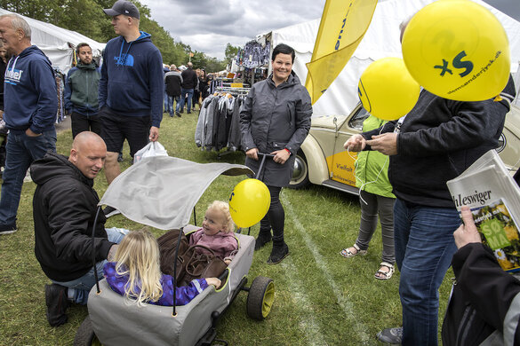 Zwei kleine Mädchen in einem überdachten Bollerwagen haben am Stand der Schleswigschen Partei einen gelben Ballon erhalten.
