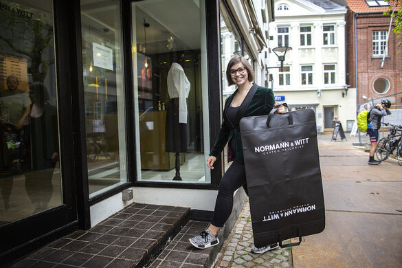 Camilla Witt geht mit einem Kleidersack im Arm in ihren Laden an der Ramsharde hinein.