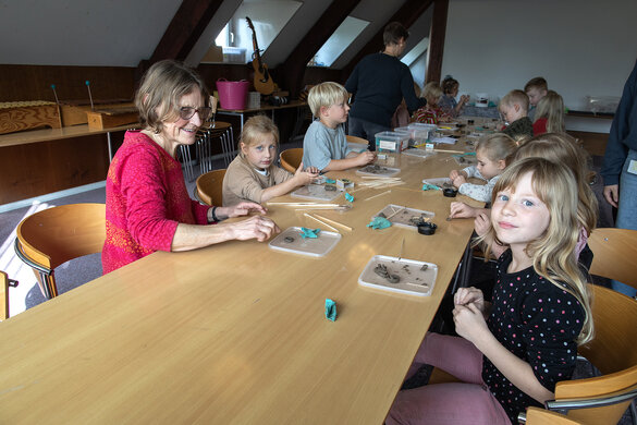 Eine lange Tafel, Kinder sitzen jeweils links und rechts am Tisch. Vor Ihnen ihre Tonkunstwerke auf kleinen Plastikdeckeln.