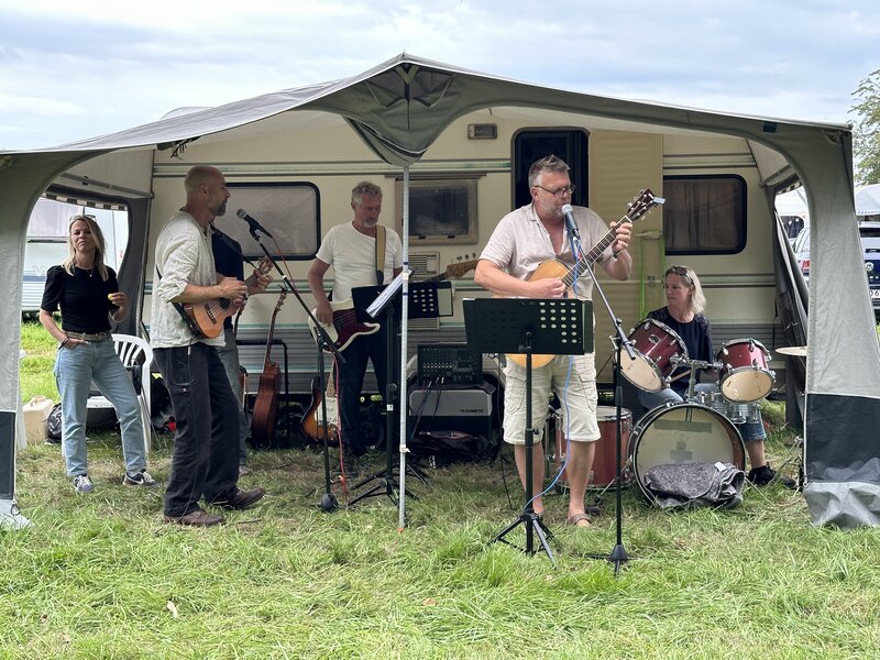 Eine Band spielt im Vorzelt eines Campingwagens Musik