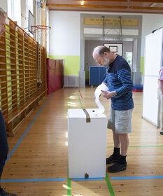 Jens Knudsen steckt seinen Wahlzettel in den Schlitz der Wahlurne.