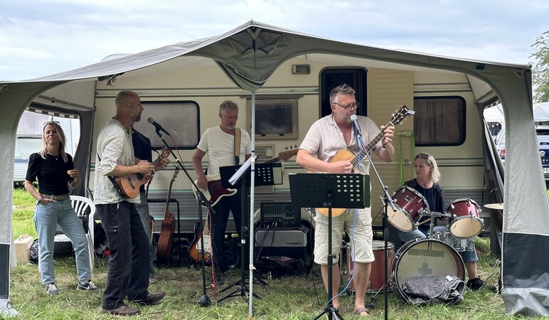 Eine Band spielt im Vorzelt eines Campingwagens Musik